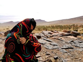 Full length of man wearing hat on rock against sky