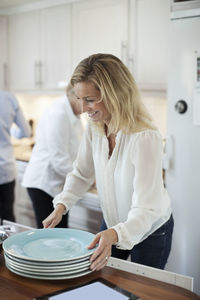 Woman arranging plates in kitchen