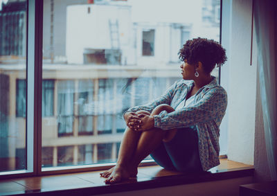 Woman looking away while sitting by window