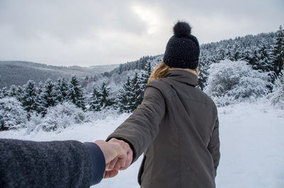 Cropped image of man holding woman hand during winter