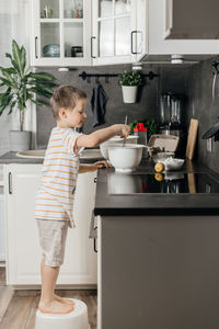 The boy prepares dough for biscuit or baking in the kitchen. the child mixes the ingredients with 