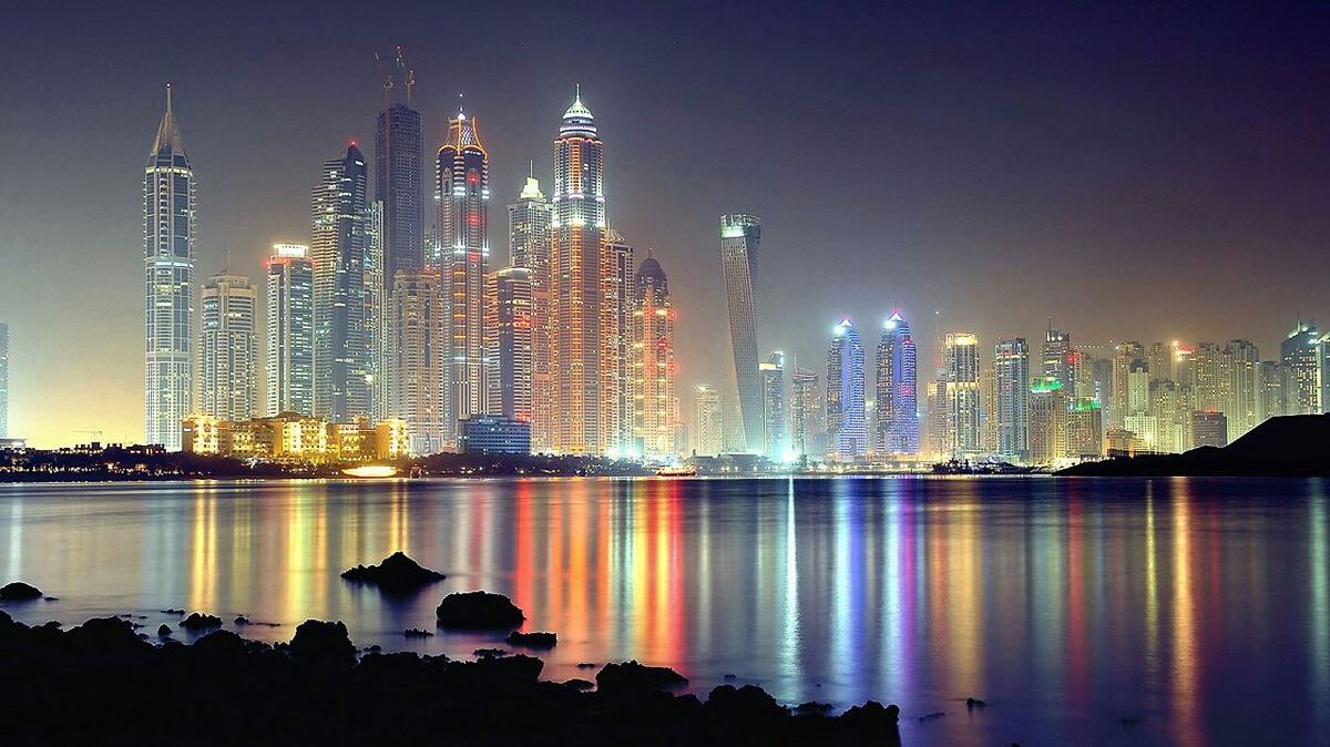 illuminated, building exterior, city, architecture, built structure, night, skyscraper, cityscape, water, tall - high, tower, modern, urban skyline, reflection, sky, office building, travel destinations, sea, capital cities, financial district