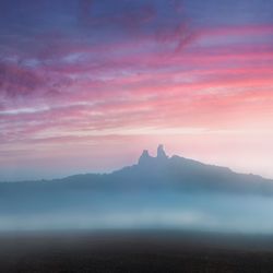 Scenic view of landscape against cloudy sky during sunset