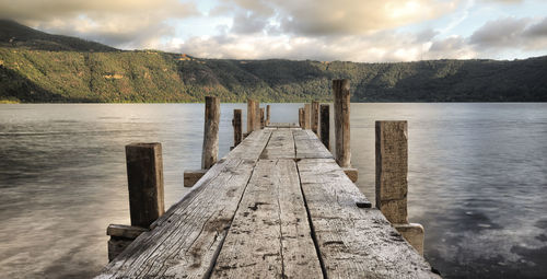 Wooden jetty on pier over lake against sky