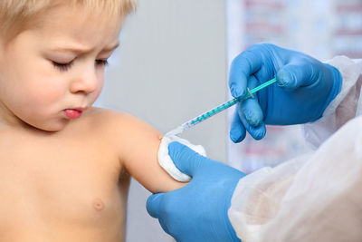 Doctor injecting vaccination in arm of a little boy. covid vaccination. doctor vaccinating child