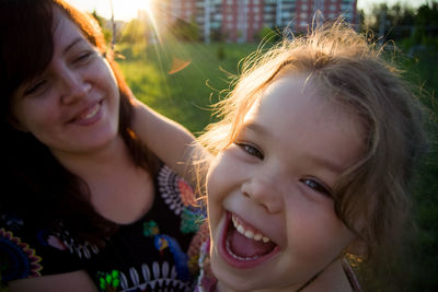 Portrait of playful girl with mother on field