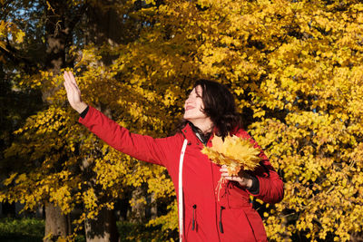 Woman standing by flowers with autumn leaves