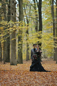 Bride and bridegroom standing at forest during autumn