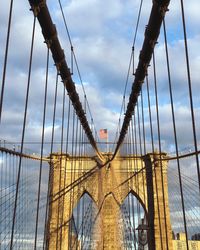 Low angle view of suspension bridge against cloudy sky