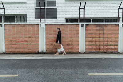 Side view of man walking on sidewalk against building