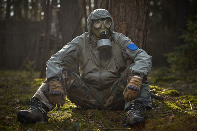 Midsection of person wearing mask against trees in forest