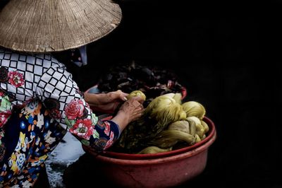 Woman with vegetables against black background