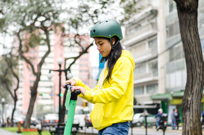 Young woman with push scooter in city