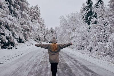 Rear view of woman standing on snow covered landscape