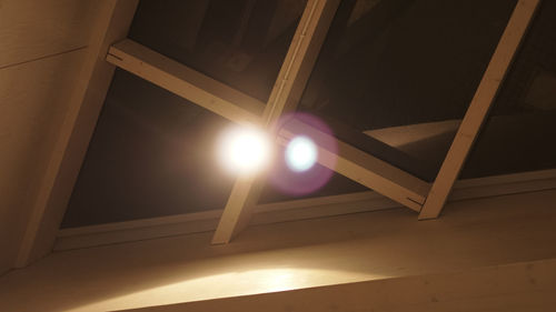 Low angle view of sunlight streaming through illuminated lamp at home