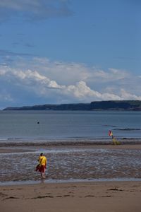 Man with umbrella on beach against sky