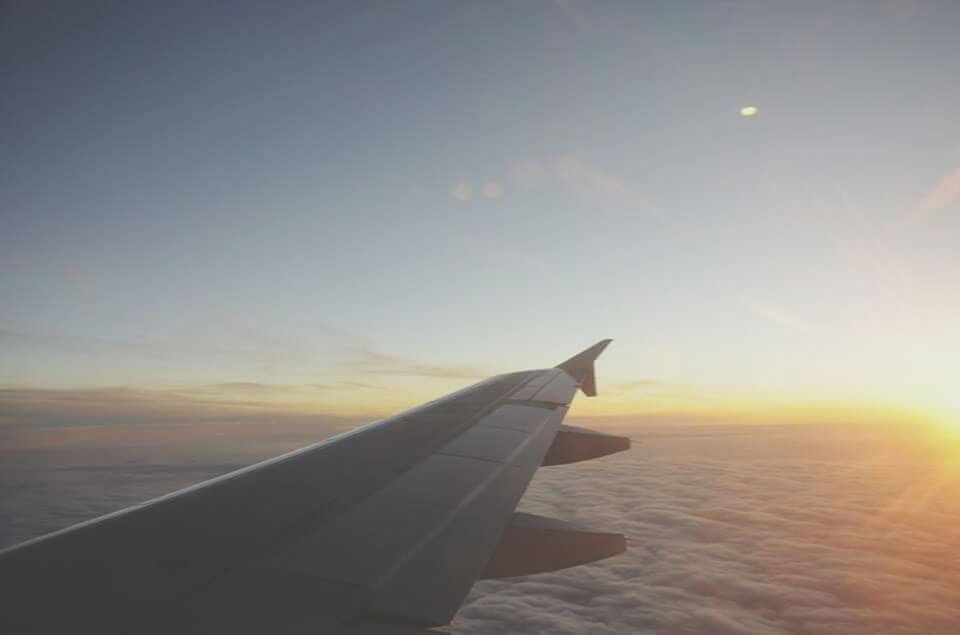 airplane, aircraft wing, transportation, sunset, air vehicle, flying, mode of transport, part of, cropped, sky, travel, sun, mid-air, orange color, journey, beauty in nature, scenics, on the move, nature, sunlight