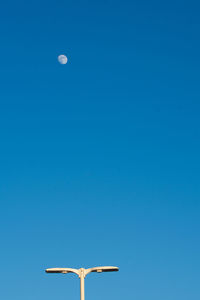 Low angle view of moon against clear blue sky