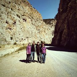 Rear view of women walking on rock against sky