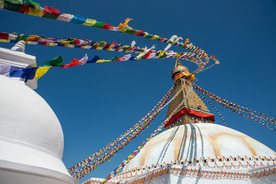 Boudha stupa, at kathmandu city in nepal against blue sky, with colorful flags waving.