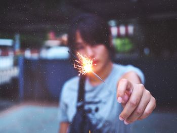 Woman holding sparkler at night