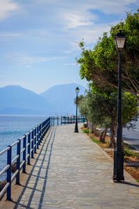 Wooden posts on street by sea against sky