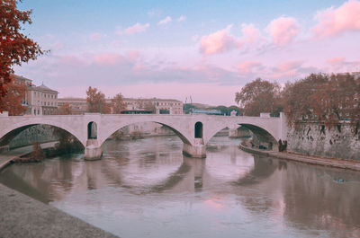 Bridge over river against sky in city