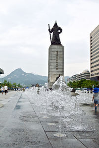 Statue in city against sky