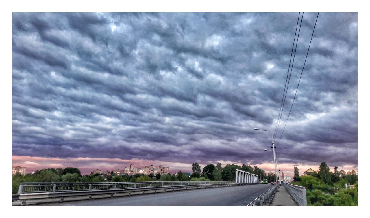 ROAD AGAINST STORM CLOUDS OVER LANDSCAPE