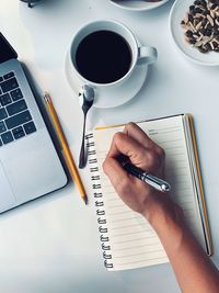 Cropped image of hand holding coffee cup on table