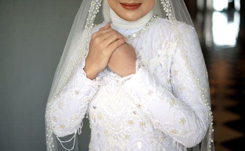 Portrait of young woman as bride standing against in white wedding dress with black background