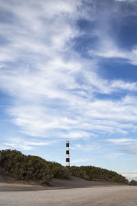 Lighthouse amidst buildings against sky