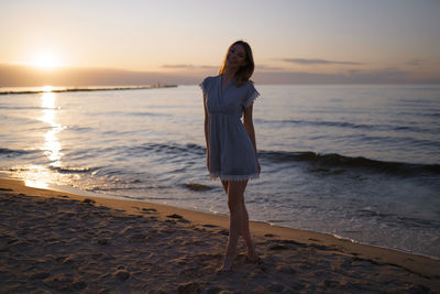 Full length of woman standing on beach during sunset