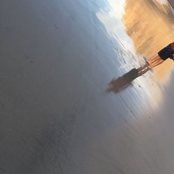 Low section of person standing on wet shore