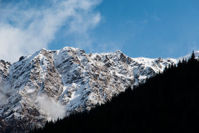 Low angle view of snow covered mountains against sky