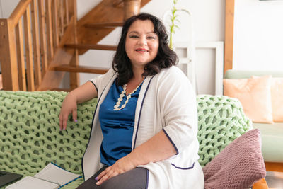 Portrait of smiling woman sitting on bed at home