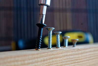 Close-up of screwdriver fixing nail in wood
