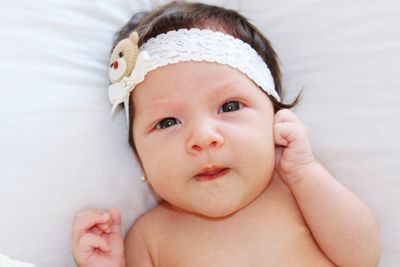 Portrait of cute baby girl relaxing on bed