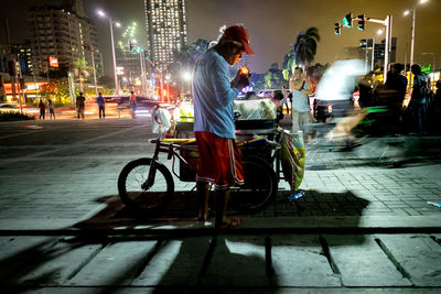 Man riding bicycle on illuminated city at night