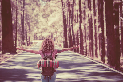 Rear view of woman walking on road in forest