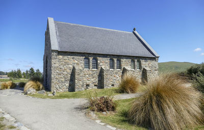 Old building by road against clear blue sky