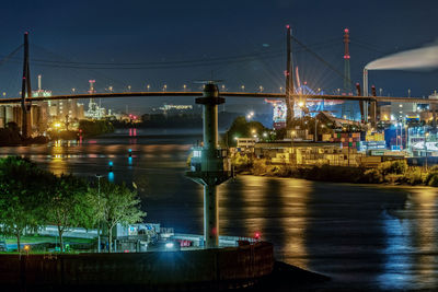 Illuminated bridge over river against sky at night