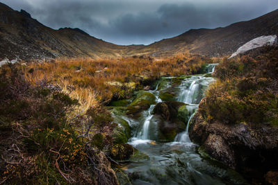 Scenic view of waterfall against sky