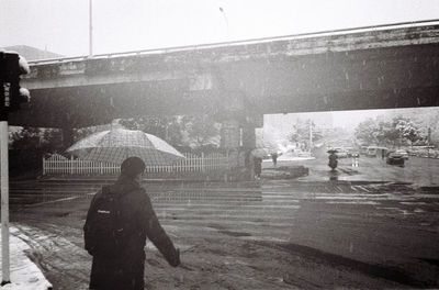 Rear view of person walking on street in rain