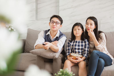 Full length of a smiling young woman sitting on sofa