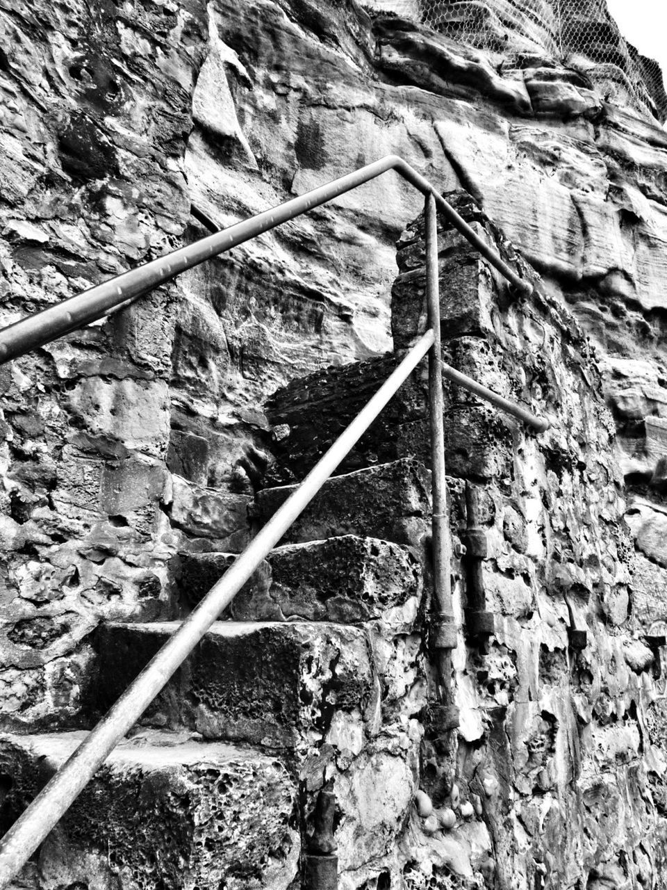 rock - object, built structure, architecture, railing, mountain, steps, low angle view, stone wall, day, old, stone - object, metal, tree, steps and staircases, outdoors, no people, nature, abandoned, textured, sunlight