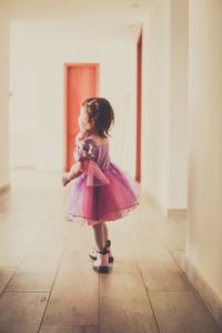 Side view of girl wearing dress while standing in corridor