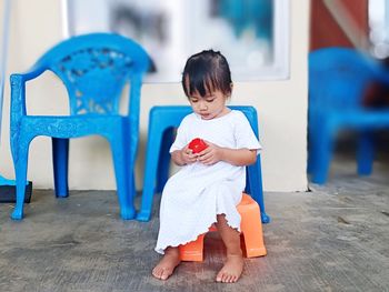 Cute boy looking away while sitting on blue wall