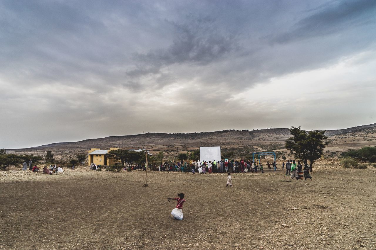 sky, cloud - sky, large group of people, cloudy, beach, lifestyles, leisure activity, person, building exterior, men, sand, architecture, built structure, cloud, day, mixed age range, vacations, shore, nature