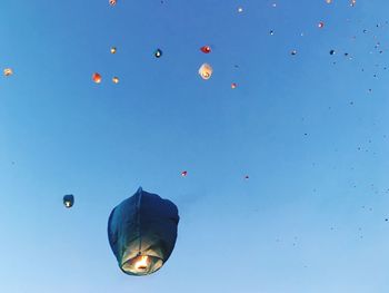 Low angle view of balloons against clear blue sky